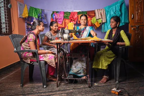 Group of women sitting around a tailoring machine